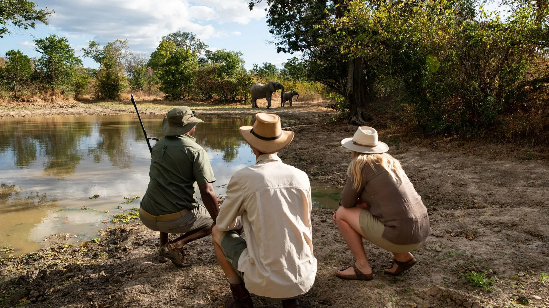 A trio of people sitting on the ground, appearing relaxed and conversing in a natural outdoor setting