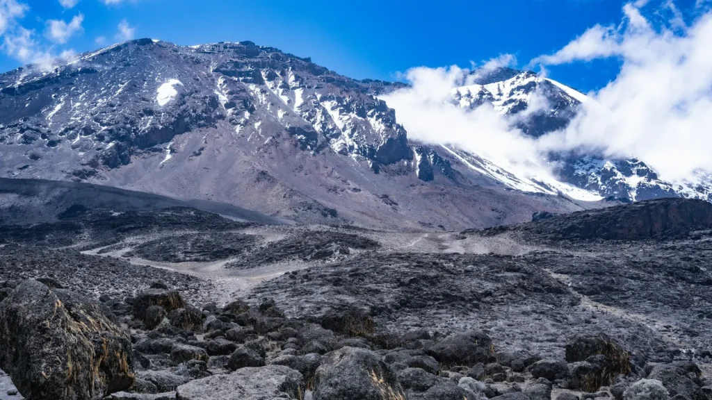 Mountain range of Mount Kilimanjaro, featuring rocky terrain and a snow-covered peak.